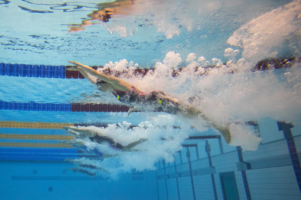 An underwater image of a female swimmer jumping in the water