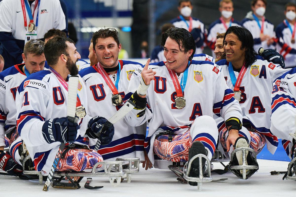 A group of USA Para ice hockey players with their gold medals on an ice rink