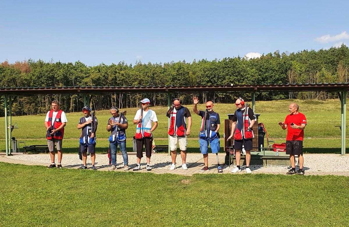 Seven men standing on a shotgun shooting range on a sunny day