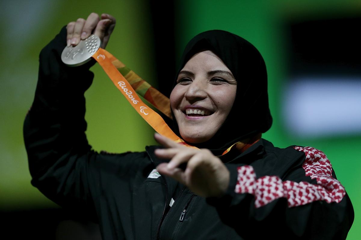 A woman with a veil smiling and showing her medal