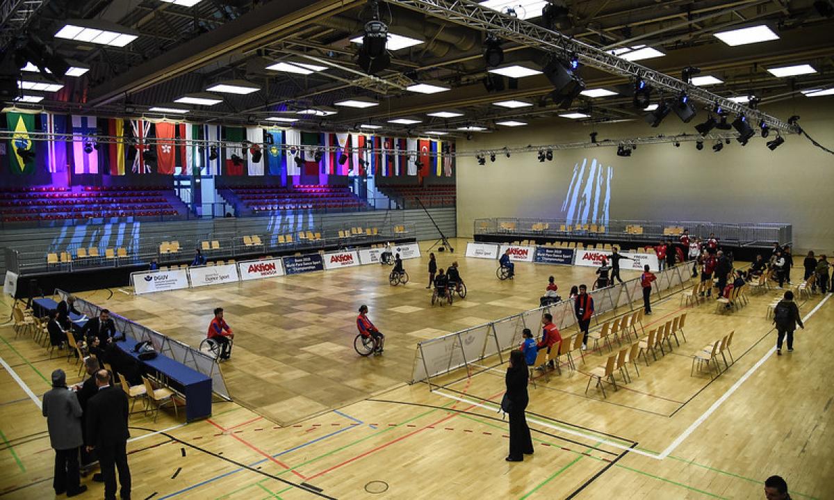 An indoor court with a group of Para dancers practicing observed by a group of people around the court