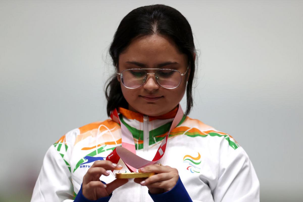A young woman looking at her gold medal