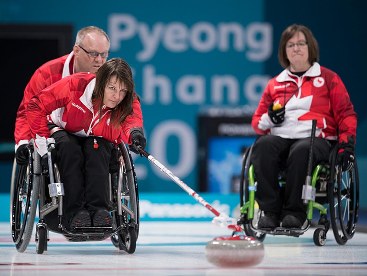 Canadian wheelchair curler Ina Forrest pushes the stone on the ice rink
