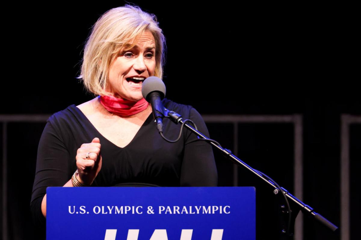 A woman makes a speech at a tribune marked with the words 'U.S. Olympic and Paralympic Hall of Fame'.