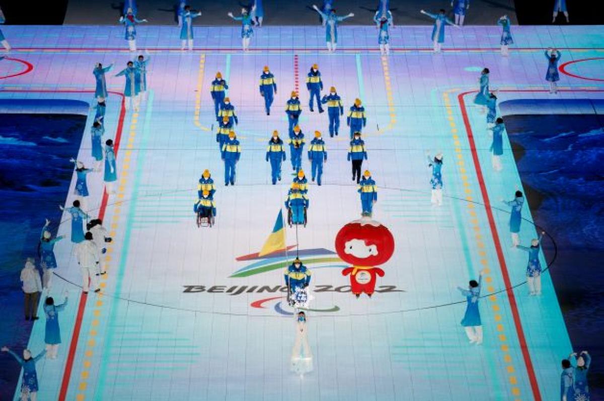 Flagbearer Maksym Yarovyi, a Ukrainian flag attached to his wheelchair, leads the Ukrainian delegation into the Opening Ceremony of the Beijing 2022 Winter Paralympic Games.