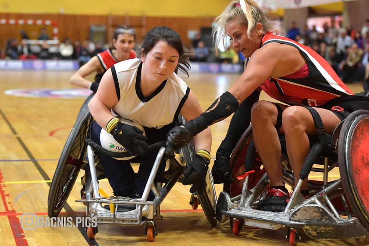 Two female wheelchair rugby players compete