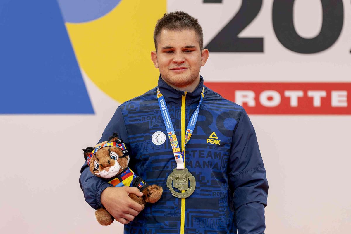 Florin Alexandru Bologa with his gold medal and mascot on the podium