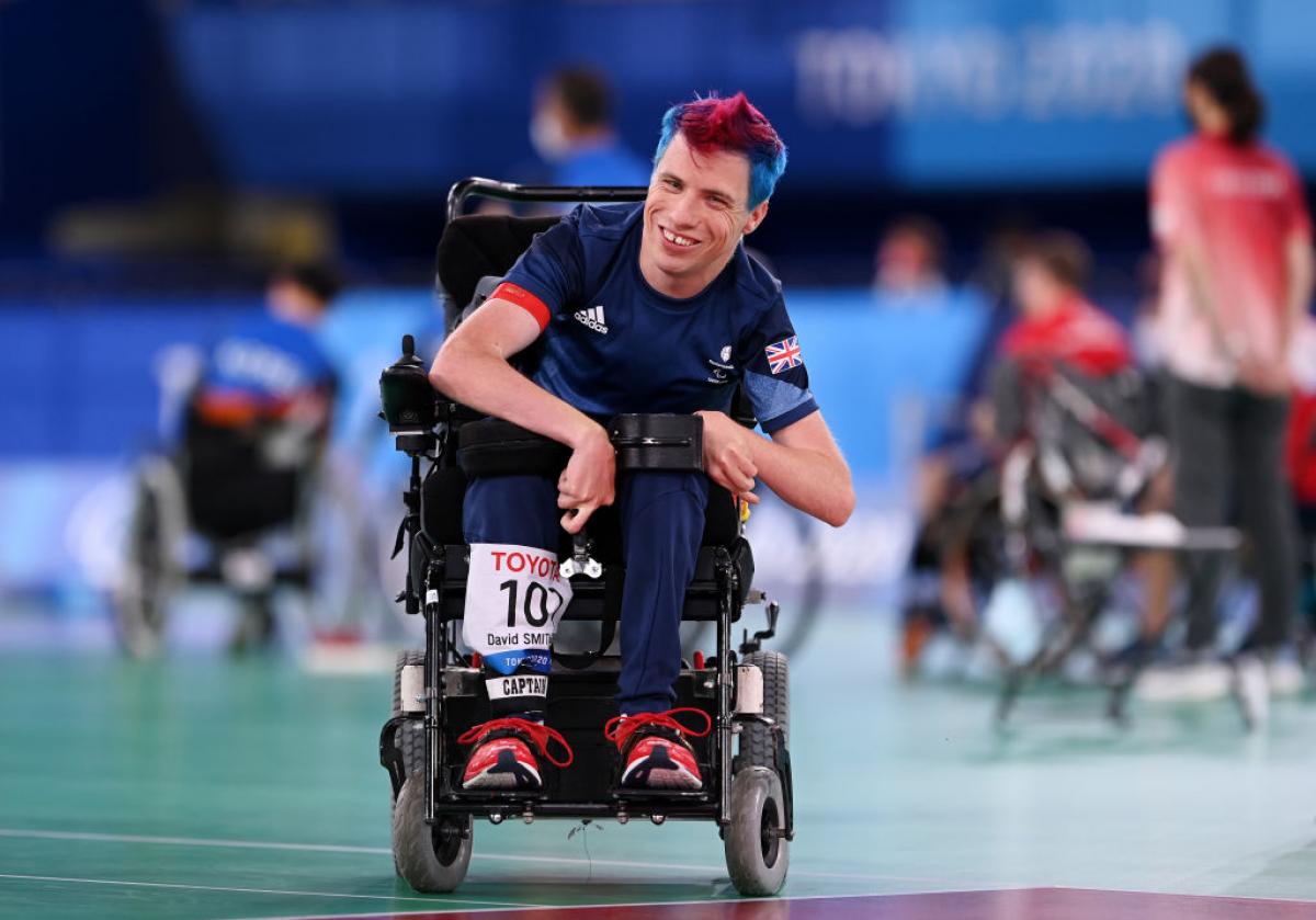 Boccia player David Smith smiles at the camera from a powered wheelchair 