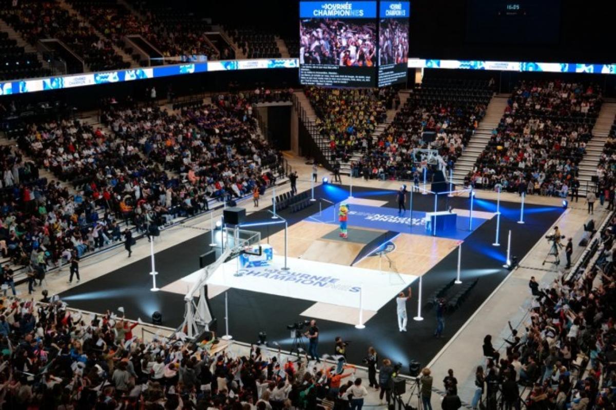 A wide shot of a basketball court. Many people are in the stands