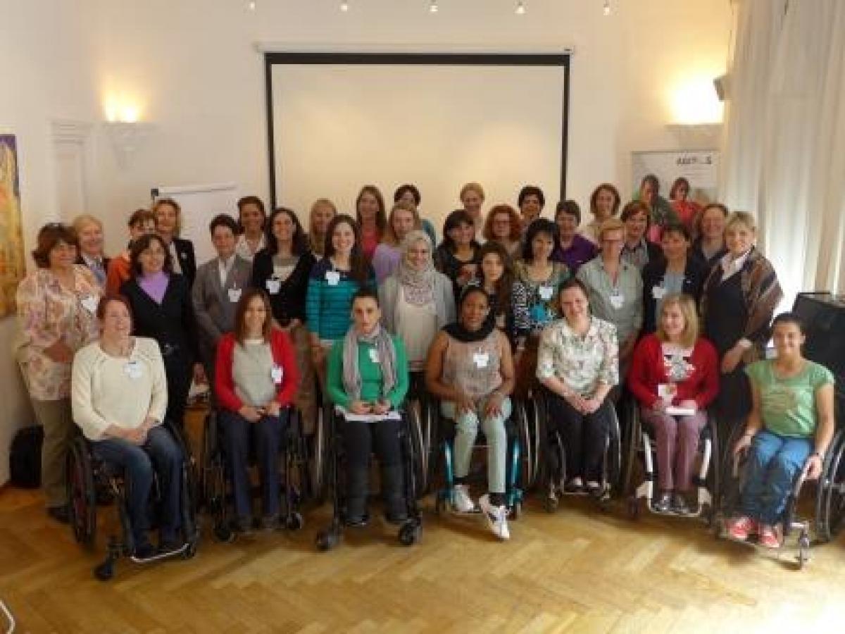 WoMentoring launch Vienna Group shot of women (standing and in wheelchairs) in front of a white wall.