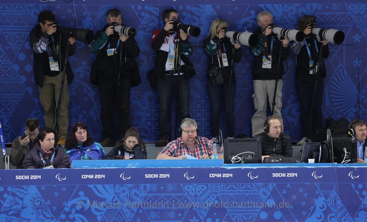 A row of sport photographers taking pictures of ice sledge hockey at Sochi 2014.