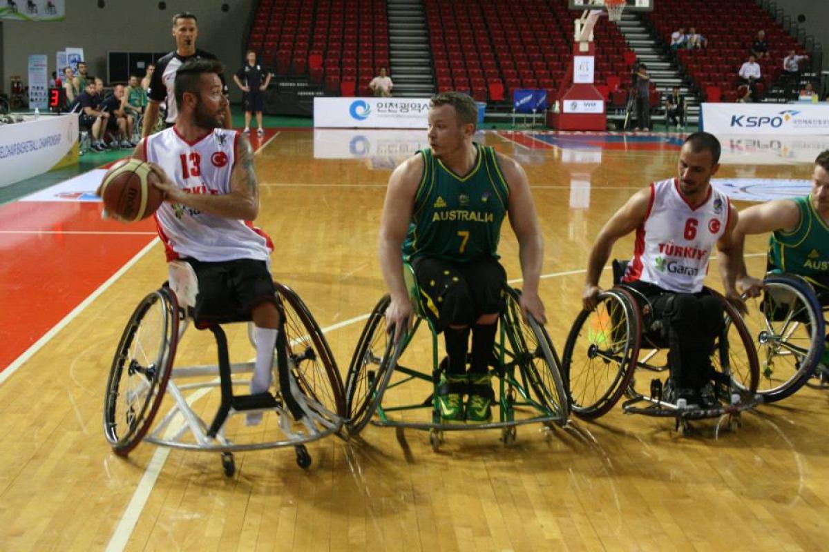 Three wheelchair basketball players fight for the ball