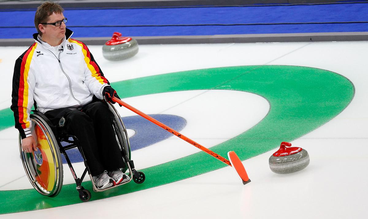 Man in wheelchair on the ice, pointing on a point on the ice