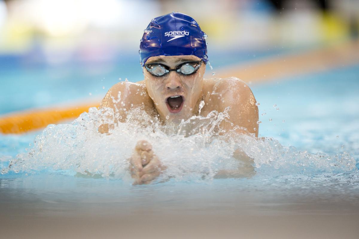 Swimmer with blue swim cap doing breaststroke