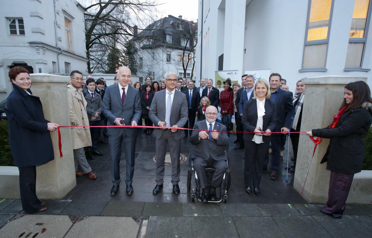Picture of four people cutting a red ribbon to open a new building.