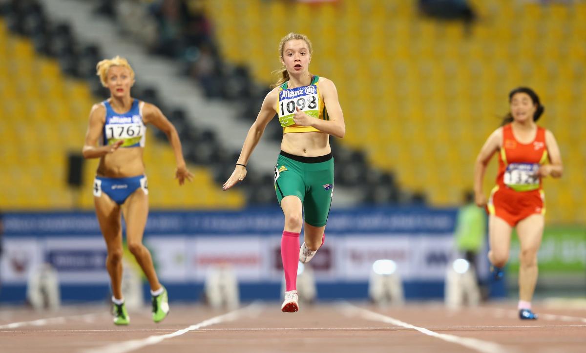 three females running, one wearing green, one blue and one red