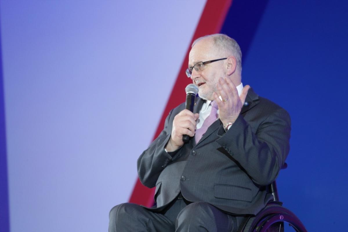 Man in wheelchair speaking on a stage