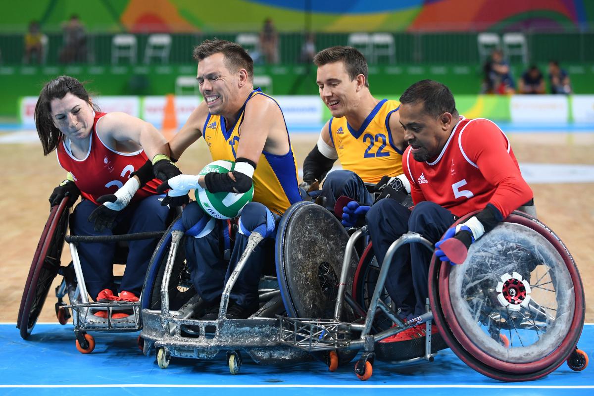 Four wheelchair rugby players fighting for the ball.