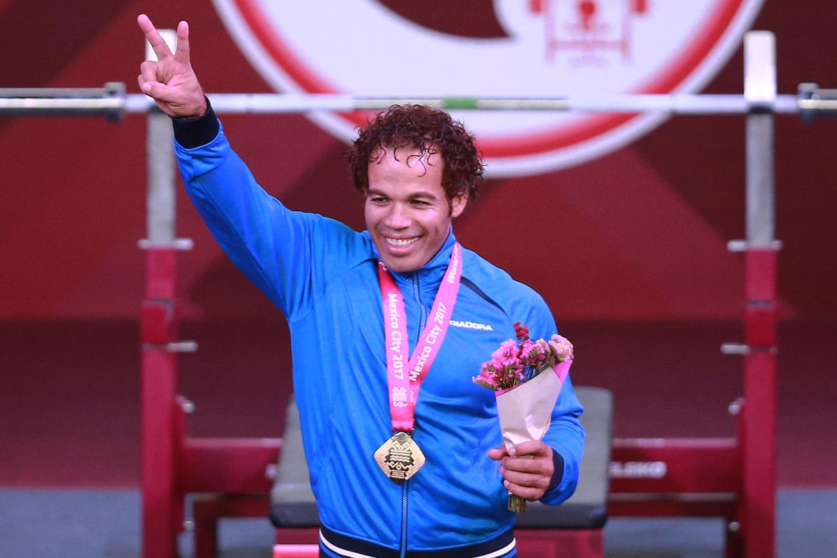 a male powerlifter celebrates his gold medal on the podium