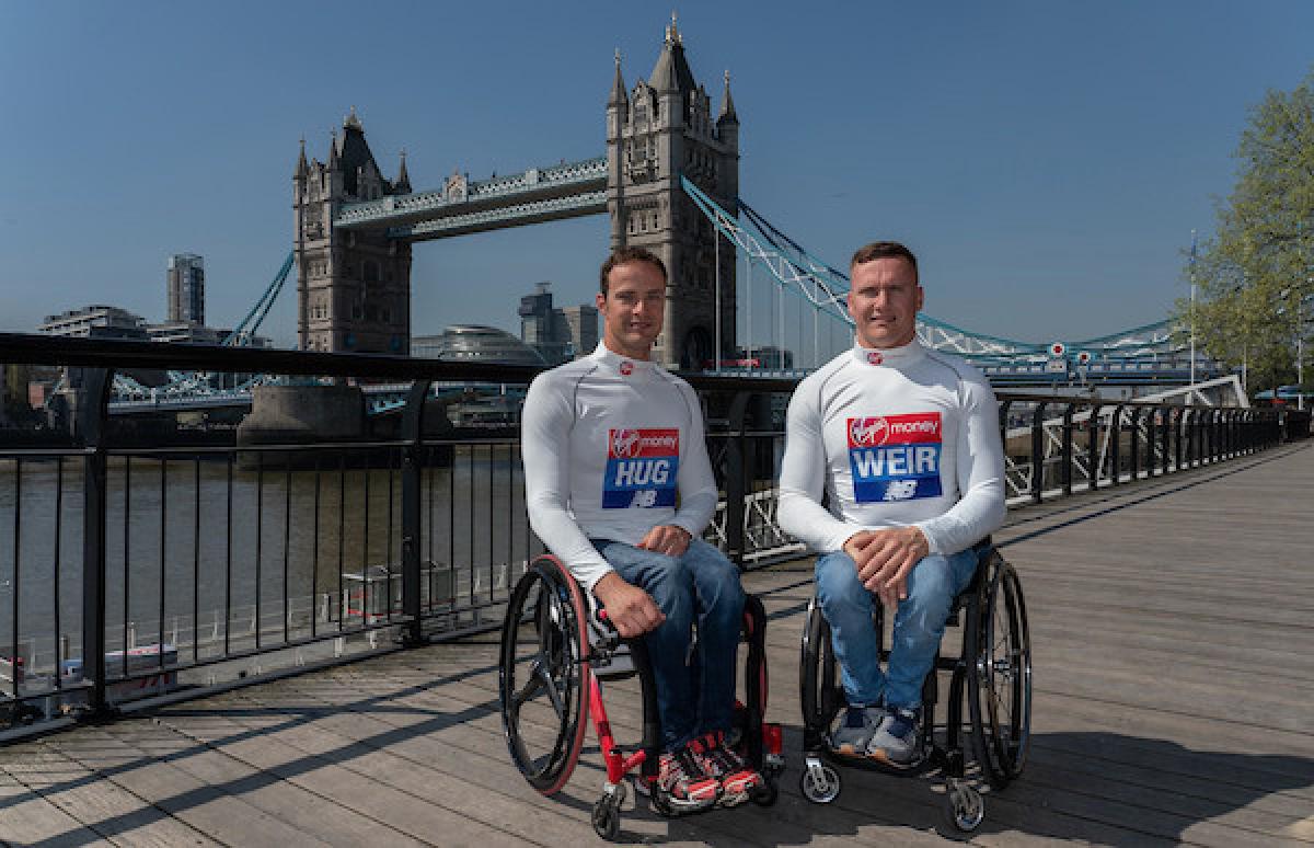 Two men in wheelchairs in London with the Tower Bridge in the background