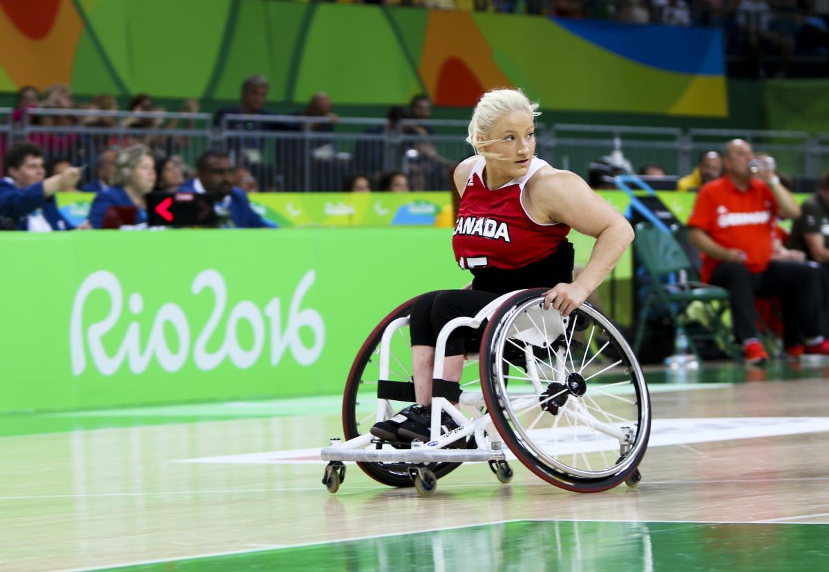Women in wheelchair dribbles basketball