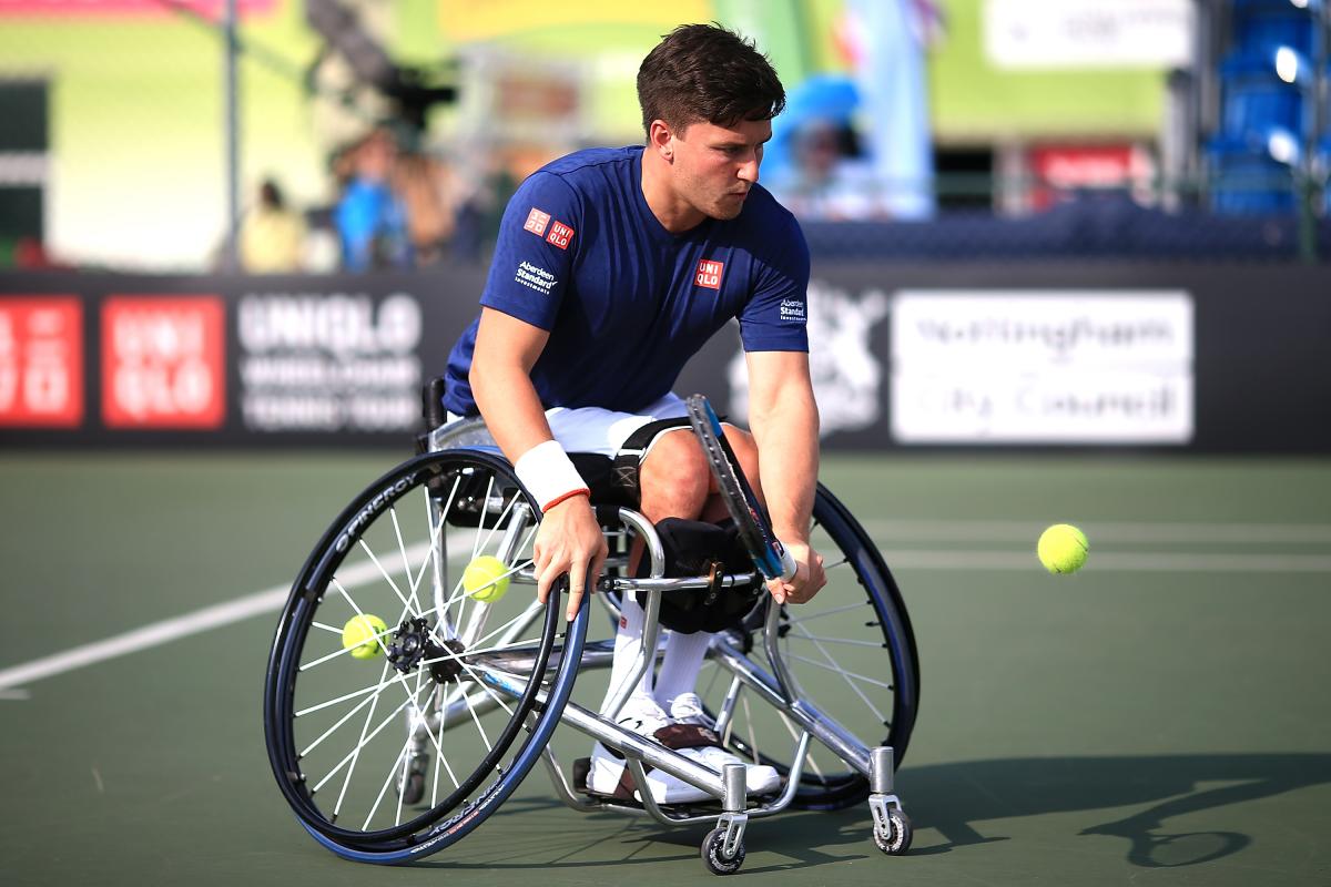 male wheelchair tennis player Gordon Reid plays a low backhand on a hard court