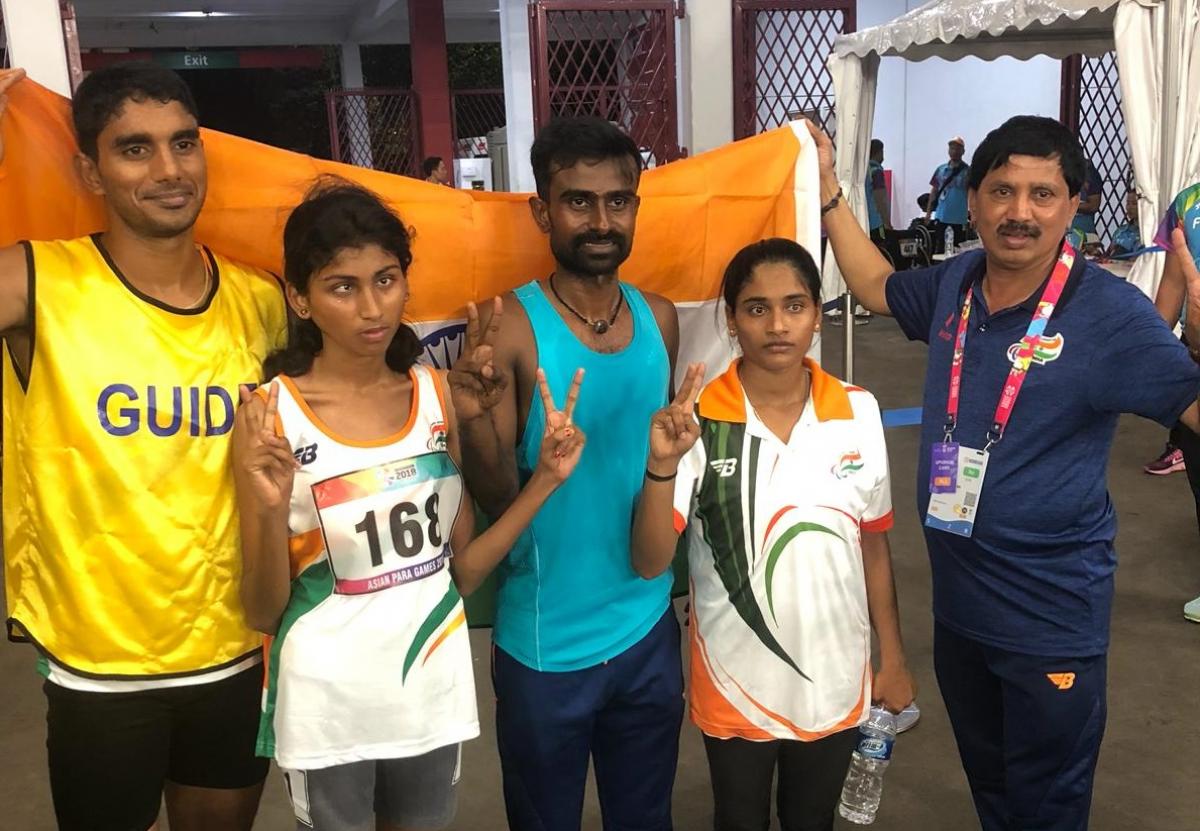 female Para athlete Rakshitha Raju standing with her guide in front of an India flag