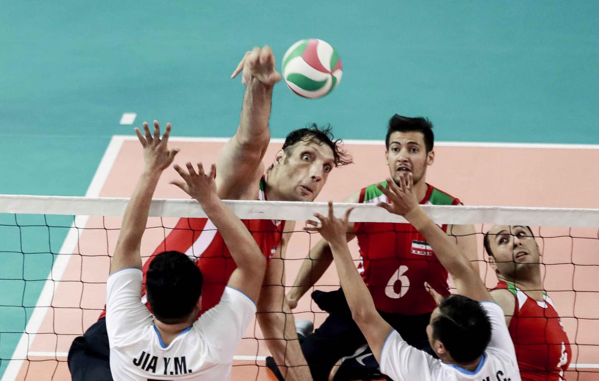 male sitting volleyball player Morteza Mehrzadselakjani blocks a ball over the net