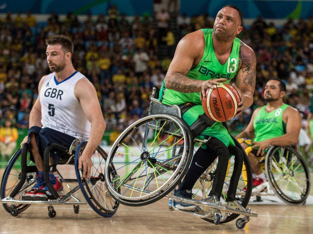 male wheelchair basketballer Leandro de Miranda shields the ball from another player