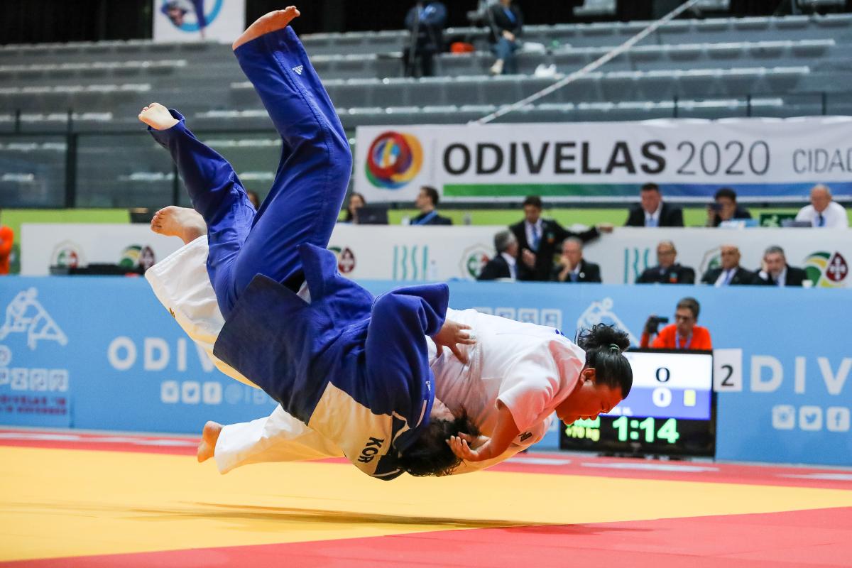 Judokas holding each other while falling onto the tatami