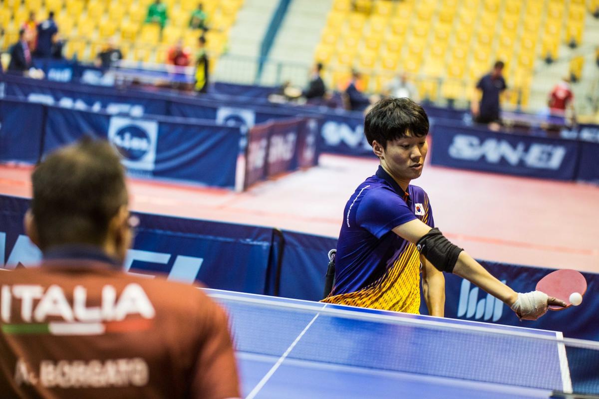 Male Korean table tennis playe in wheelchair hits a backhand shot