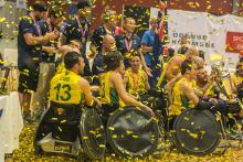 Men in wheelchairs with a big championships trophy