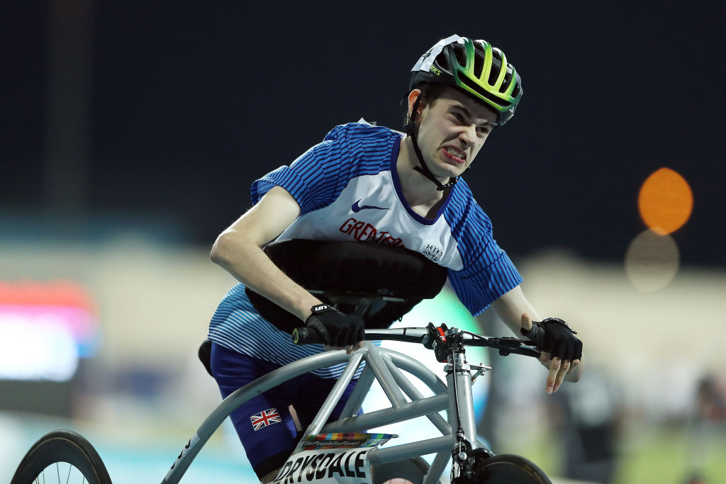 A male athlete wearing a yellow helmet is running using a metal frame