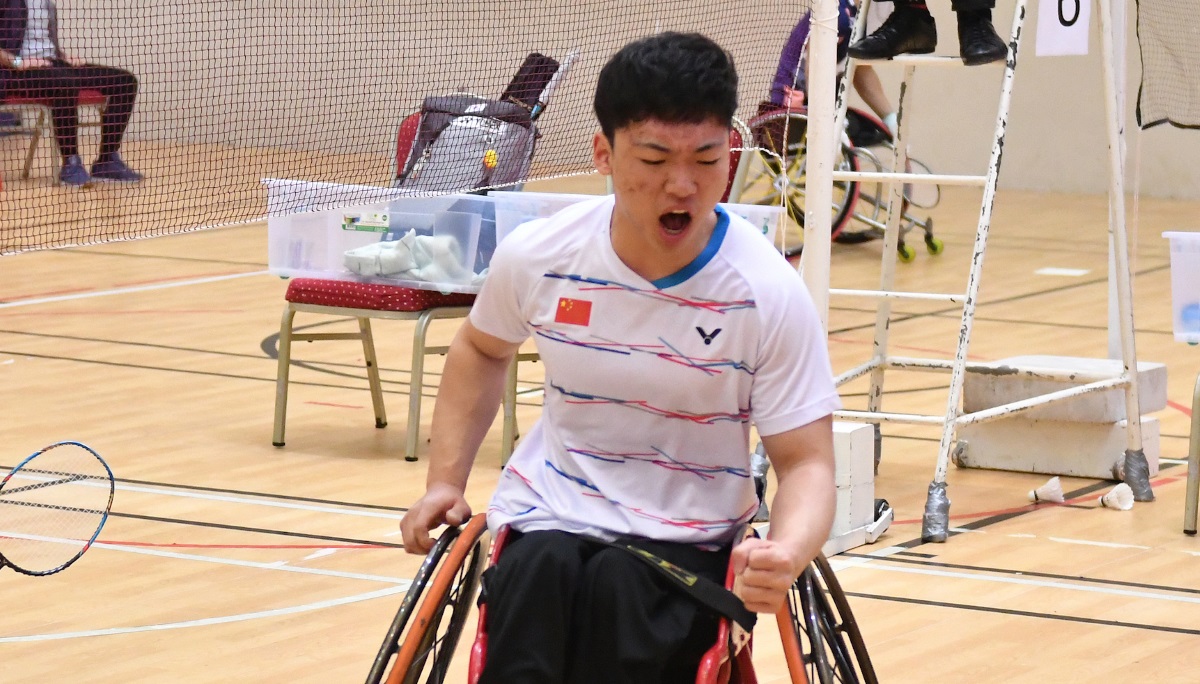 a male Para badminton player in a wheelchair pumps his fist after winning a point