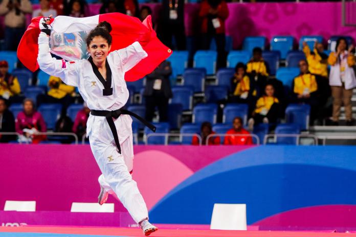 a female Para taekwondo athlete carrying the Peru flag