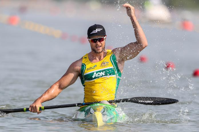 Man in kayak splashes water to celebrate victory