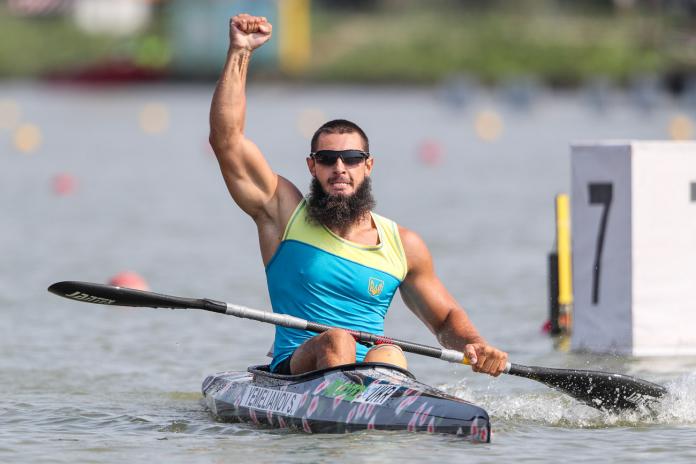 Man in kayak raises fist in air to celebrate