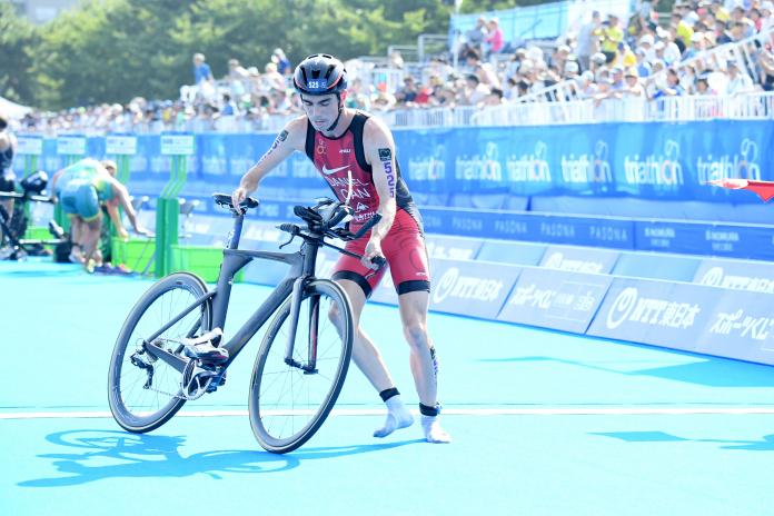 a male Para triathlete turns to get onto his bike