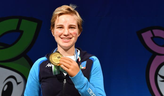 Female fencer smiles holding gold medal