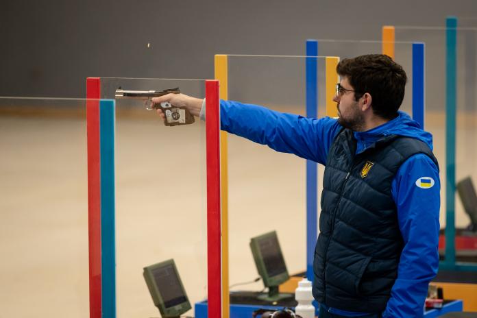Man stands holding pistol ready to hit target