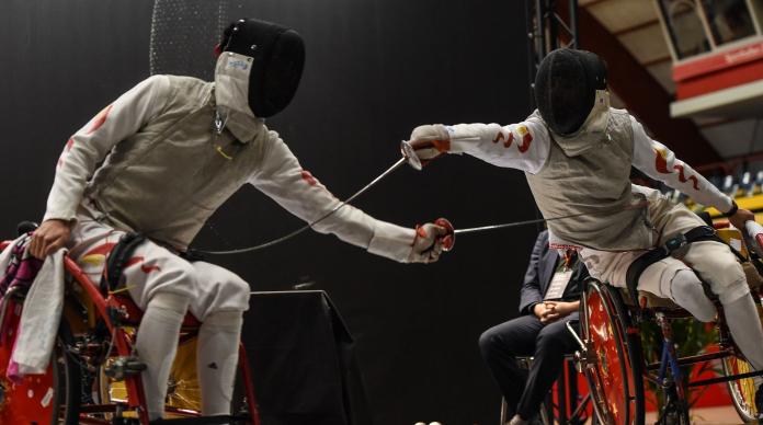 Two male Chinese wheelchair fencers battling on the piste