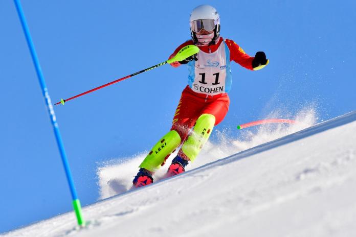 Stehender chinesischer Skifahrer fährt den Berg hinunter