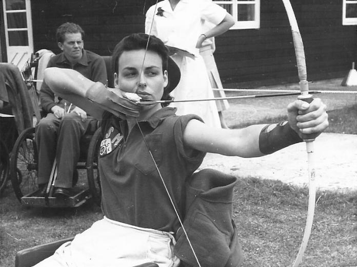 Black and white photo of woman aiming her bow and arrow