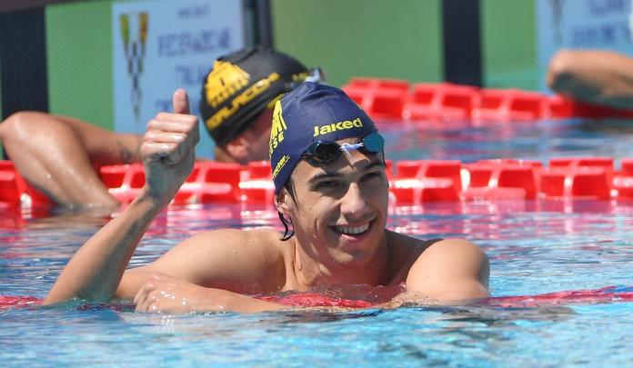 A male swimmer inside the pool giving thumbs up