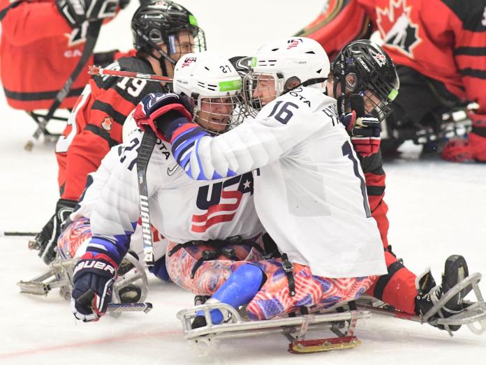Two men in sledges celebrating with the USA uniform in a Para ice hockey game