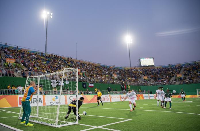 Sighted coach guides football 5-a-side players from behind the goal