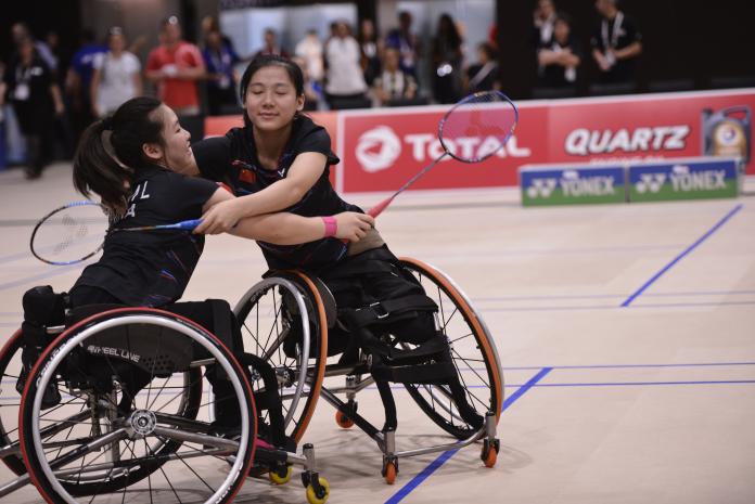 Badminton players on wheelchairs hugging each other