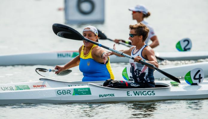 Two female canoe athletes congratlate each other after a race