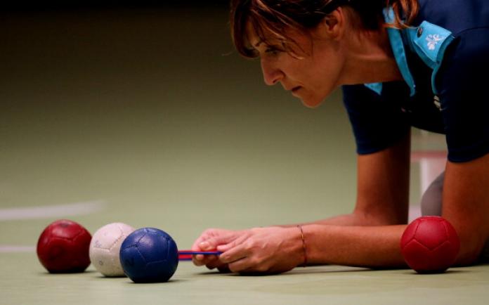 A woman measures boccia balls using a tool called calipers 