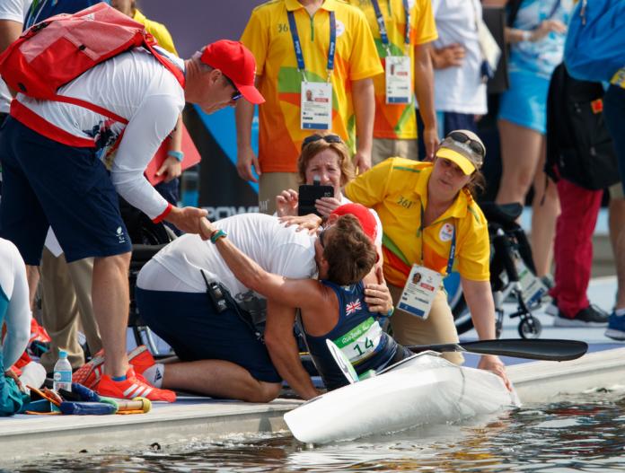 Woman in canoe congratulated by team staff